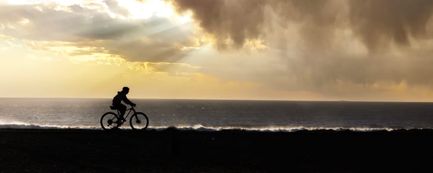 The Serene Coastline: A Man Cycling Along the Sandy Beach with Crashing Waves in the Background