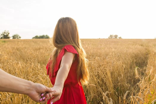Follow me, Beautiful young woman holds the hand of man in a wheat field