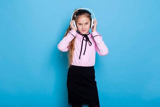Schoolgirl girl listens to music with headphones and dances