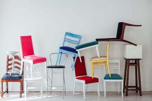 many different chairs stand in the white room