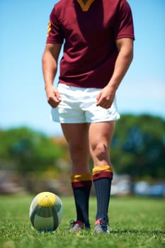 Legs, athlete and player with rugby ball for sports workout or training on a field. Feet, fitness and man ready for competitive exercise in a uniform for sporty fun with an active game outdoors.
