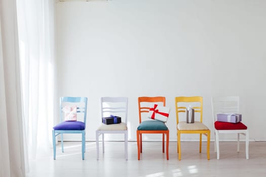 multicolored chairs with gifts in the interior of the white room