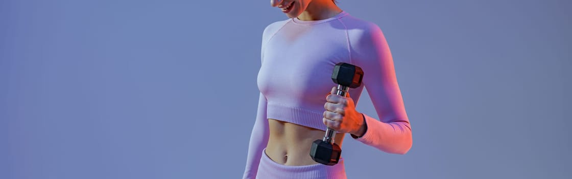 Fitness woman doing exercises with dumbbells on studio background. Strength and motivation