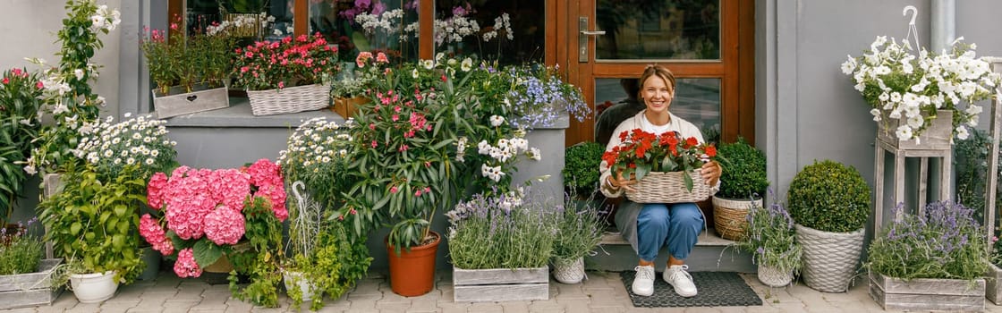 Smiling woman florist business owner sitting with houseplants on background of floral store