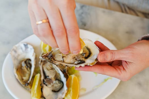 Girl enjoying gourmet delicacy with oysters, lemons, and silver utensils at outdoor dining event