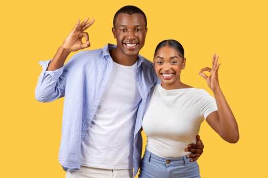 Joyful black couple showing OK signs