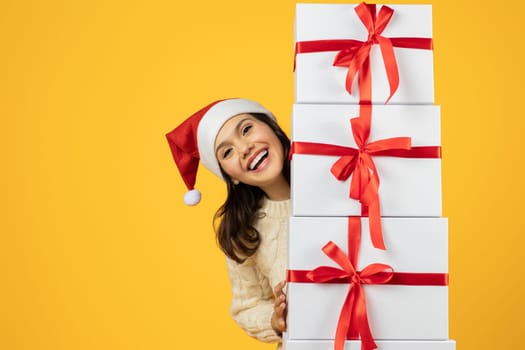 lady in festive hat with New Year gifts, yellow backdrop