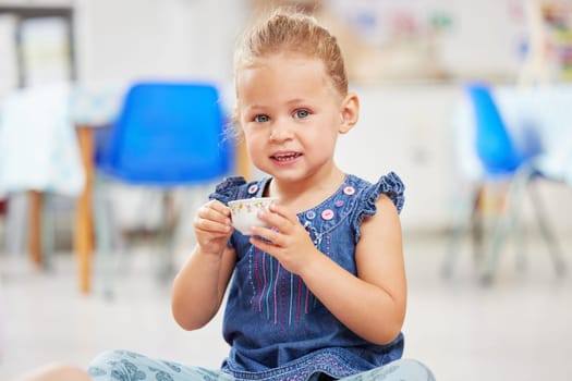 Portrait, kid or little girl with tea cup in kindergarten, daycare or classroom for playing. Youth, happy and smile for fun activity with delicious, fresh and beverage for development of motor skills