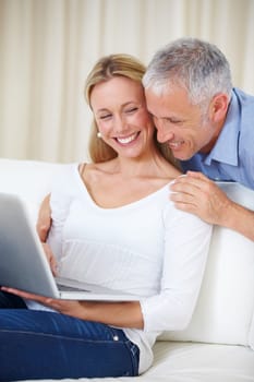 Mature couple, laptop and video call with embrace, conversation and living room couch. Social media, technology and communication with family, man and woman with connection, streaming and happy