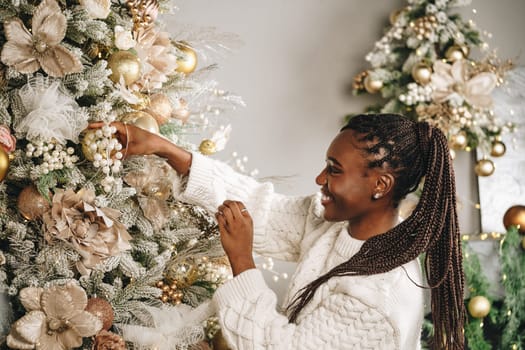 African woman preparing for winter holidays decorating Christmas tree
