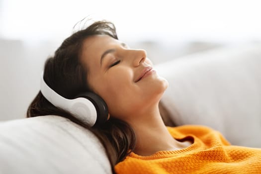 Closeup of happy young woman using wireless headphones