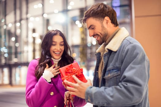 husband giving present to wife outdoor mall on winter evening