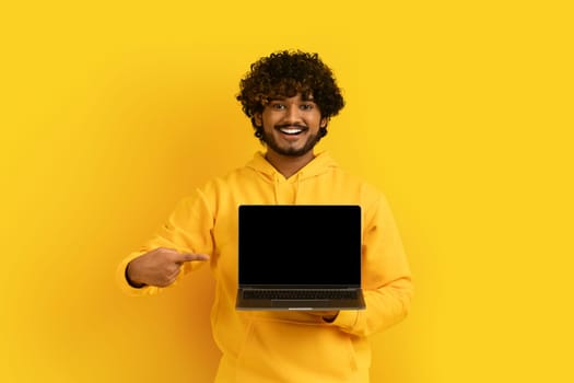 Cool young indian guy showing laptop with black screen
