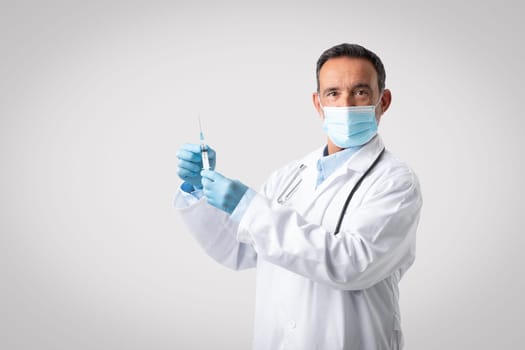 Caucasian senior man doctor in white coat, protective mask and gloves use syringe for vaccination
