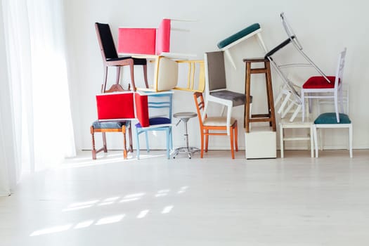 many different chairs of different colors stand at the white wall