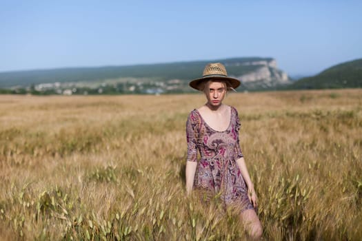 Portrait of a farmer woman in a dress in a field of rye harvest