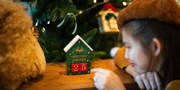 A young woman sits happily looking at a calendar counting down the days until Christmas. concept Christmas time.