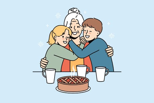Happy family of grandmother and two grandchildren hugging sitting at table with hot cake and tea