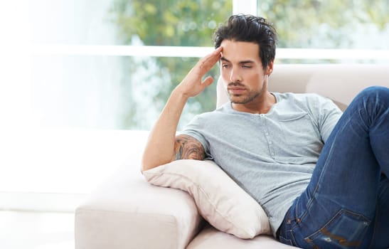 Man, thinking and sofa for unhappy in home or lonely grief mourning, broken heart or stress. Male person, sad thoughts on couch for depressed risk or loss problem from anxiety, mental health or fail