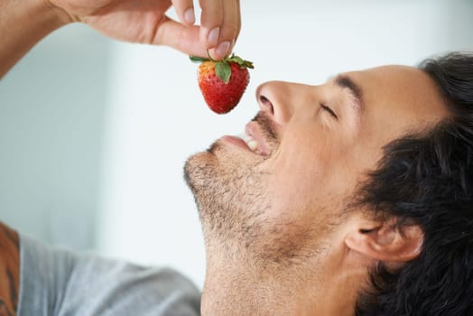 Healthy food, relax man and eating strawberry for morning diet, organic vegan lifestyle or weight loss benefits, wellness or breakfast. Vitamin C, eyes closed and face of person enjoy fruit nutrition