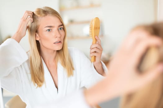 Upset woman examines and combats hair loss and flakes indoors