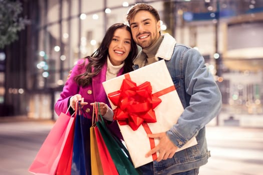 couple posing with shopping bags and Xmas gift outdoor mall