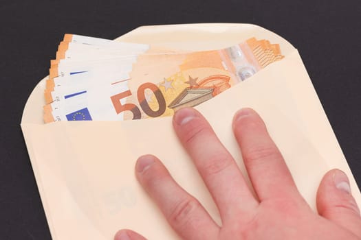 Hand Holds An Orange Paper Envelope with Stack of 50-Euro Banknotes Inside