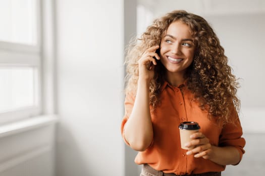 Joyful woman on call with coffee cup
