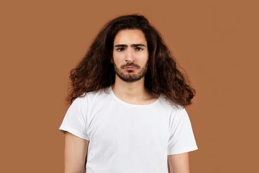 Studio Portrait Of Sad Arabic Guy With Long Curly Hair