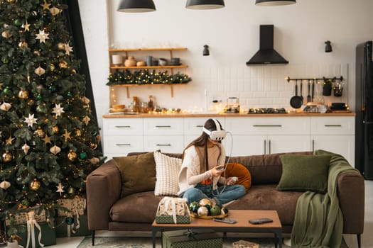 Amidst a warm Christmas ambiance at her place, a stylish young woman is seen in a virtual reality headset.