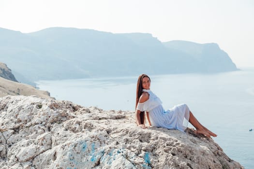 A beautiful woman with long hair in a dress looks at the landscape