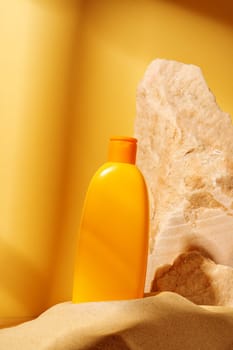 Bottle of sunscreen lotion and stone aagainst orange background