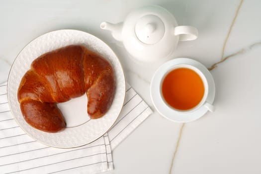 Top view of fresh baked bun with cup of tea on table