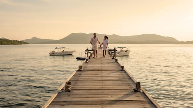 a couple walking at a wooden pier in the ocean during sunset in Samaesan Thailand