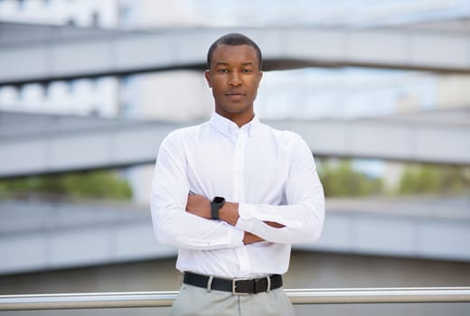 Handsome black businessman in shirt standing with arms crossed outdoors