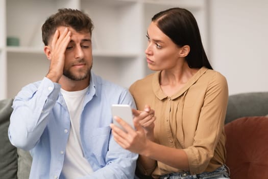 Jealous millennial wife shows smartphone confronting husband at home