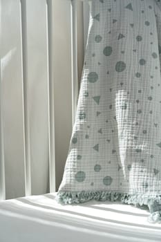Soft cotton blanket hanging on baby's bed