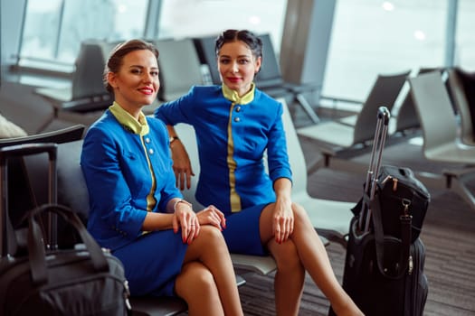 Joyful women stewardesses waiting for the flight at airport