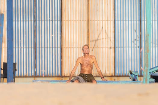 25 november 2023, Lisbon, Portugal - Shirtless Man Sitting on Surfboard in Sandy Beach