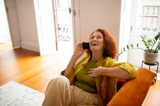 Happy Retirement. Carefree Senior Woman Laughing While Talking On Cellphone At Home