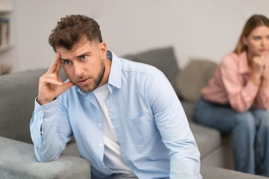 unhappy man turns away from his wife partner at home