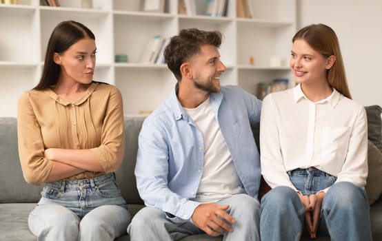 Jealous Lady Looking At Flirting Couple Sitting Together At Home