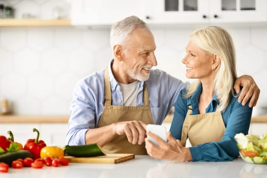 Happy Senior Spouses Ordering Grocery Delivery While Cooking In Kitchen