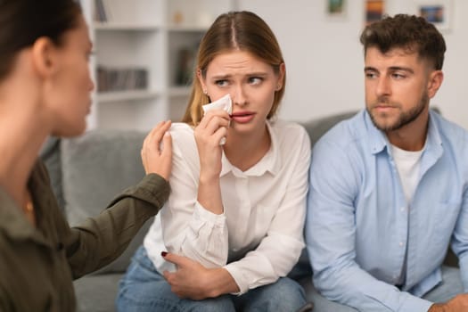 Therapist gently comforts crying woman during couples therapy session indoor