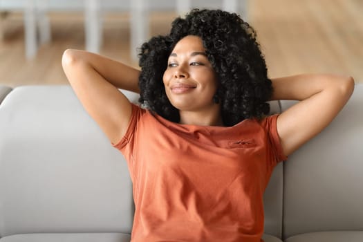 Portrait Of Calm Beautiful Black Female Leaning Back On Comfortable Couch