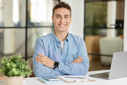 Happy handsome millennial caucasian guy manager with laptop at table