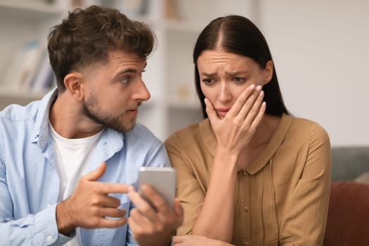 Jealous husband showing cheating messages on phone to wife indoor