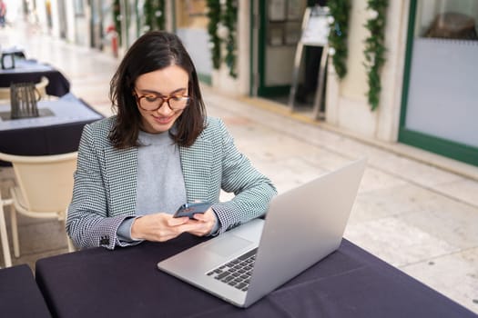 Freelance woman sitting in cafe working with laptop outdoor