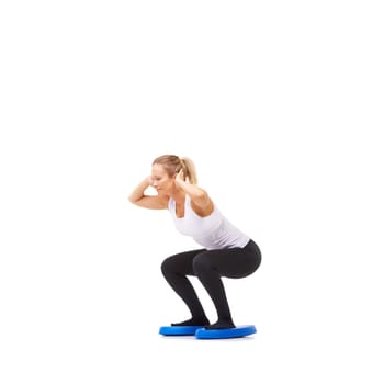 Balance, health and fitness with woman squat on disk in studio for workout, mindfulness or exercise. Wellness, challenge and training with person on white background for flexibility or aerobics