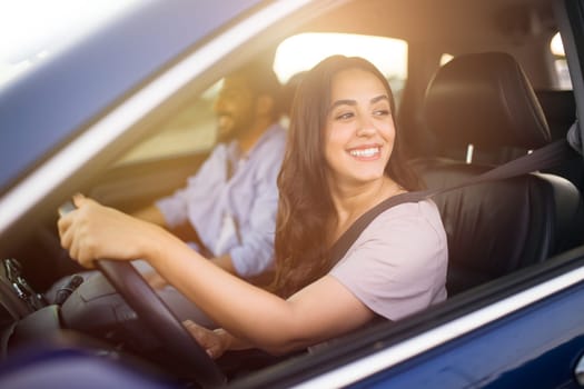 Smiling middle eastern woman driving with partner in passenger seat